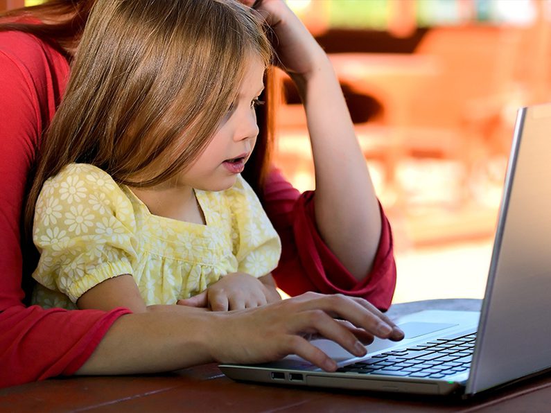 child on parent's lap on a laptop