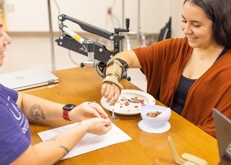 Occupational therapy student learns to use assistive device to teach future patients how to use it. Occupational therapy student learns to use assistive device to teach future patients how to use it.
