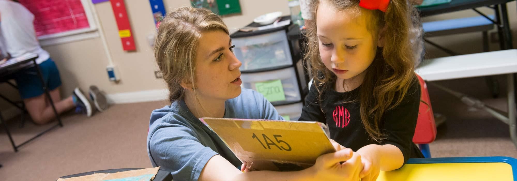 Interdiciplinary Learning student teaching child to read through UMHB education.