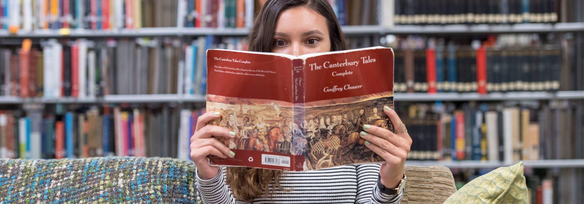 English major student reading a book in  library.