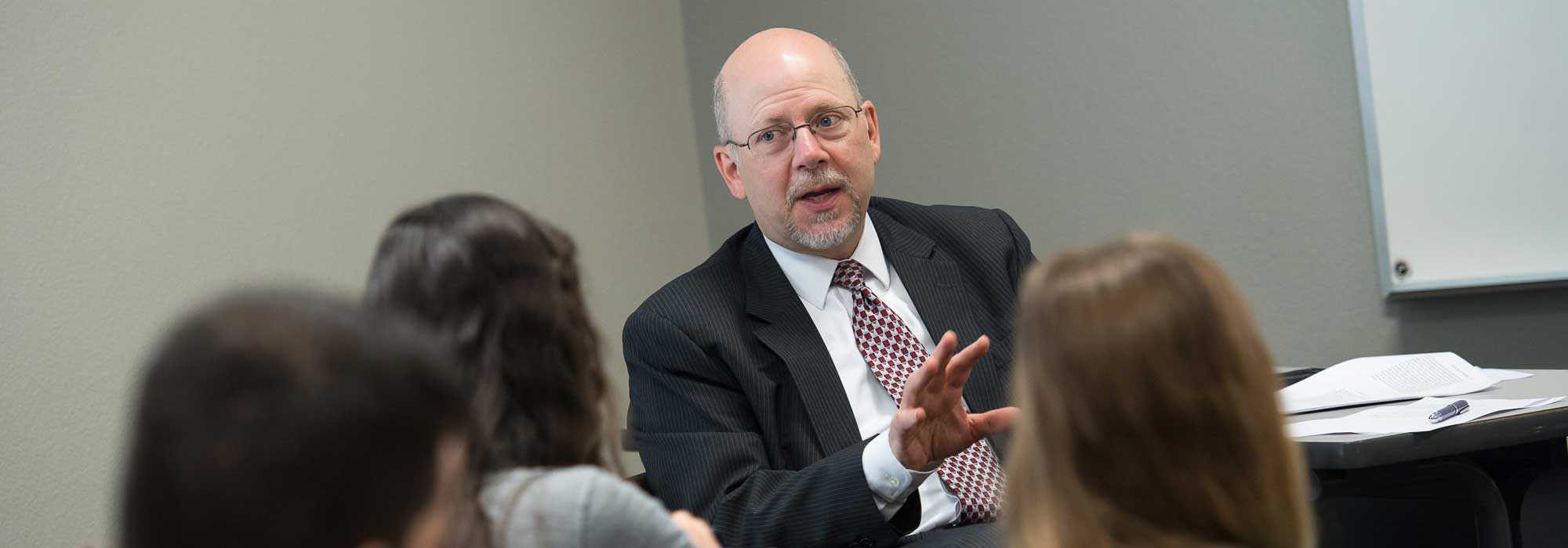 Degree in business management students speaking with management program professor about entrepreneurship at .