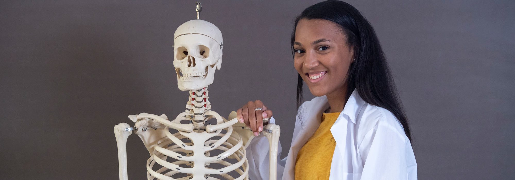 Health Professions pre-health major standing next to skelton at UMHB.