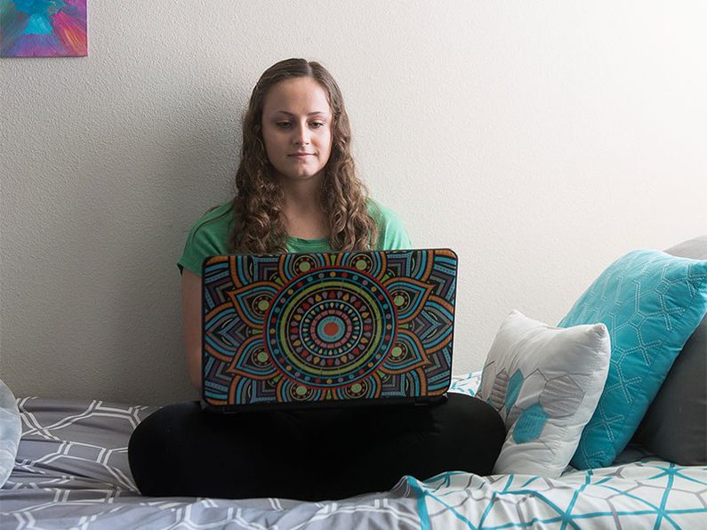 Female student working on laptop on bed